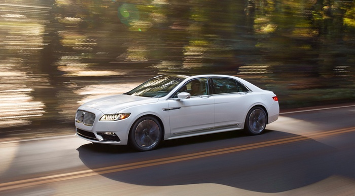 White Lincoln Continental driving on a road