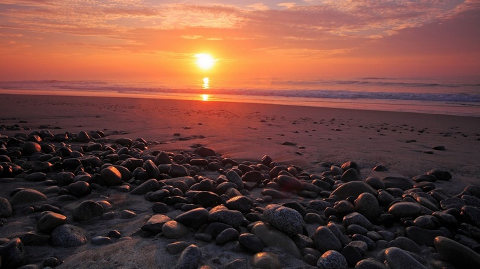 Sunset over a rocky beach with ocean waves
