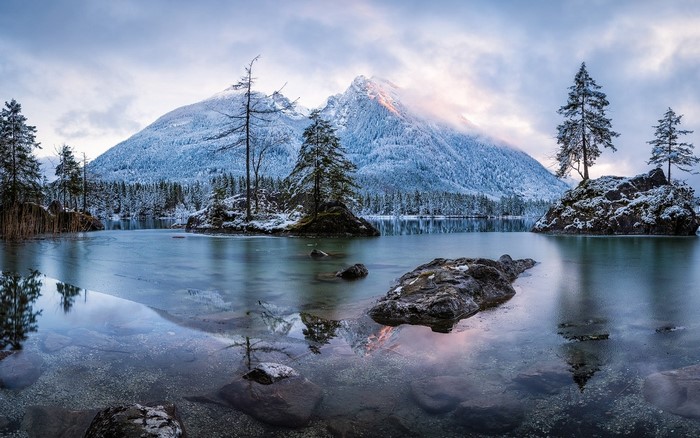 Snow-covered mountains reflected in a partially frozen lake