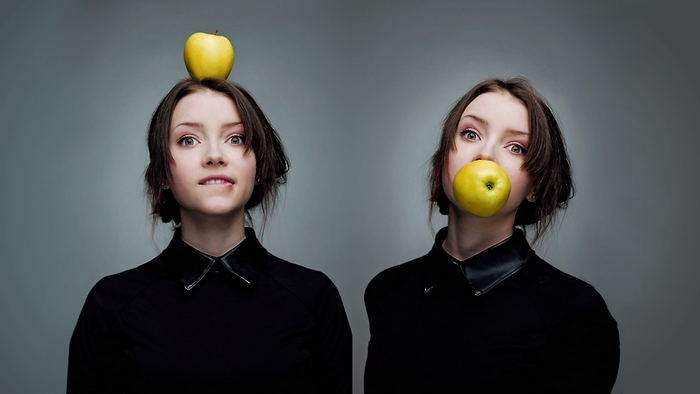 Two women with apples, one on head, one in mouth