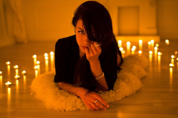 Woman lying down surrounded by candles
