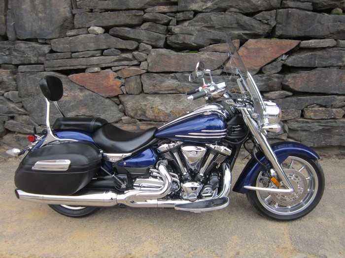 Blue Yamaha XV 1900 motorcycle parked against stone wall