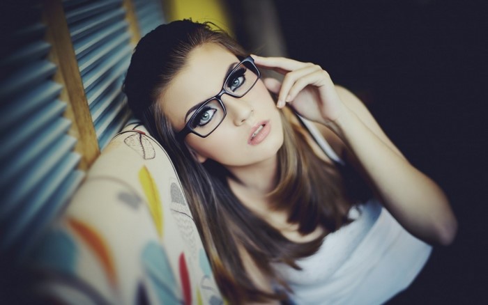 Woman with glasses posing on a couch