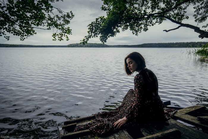 Woman with short hair sitting on a wooden pier by a lake