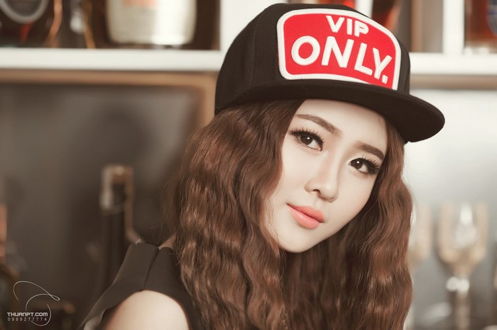 Asian woman wearing a black cap with 'VIP ONLY' patch