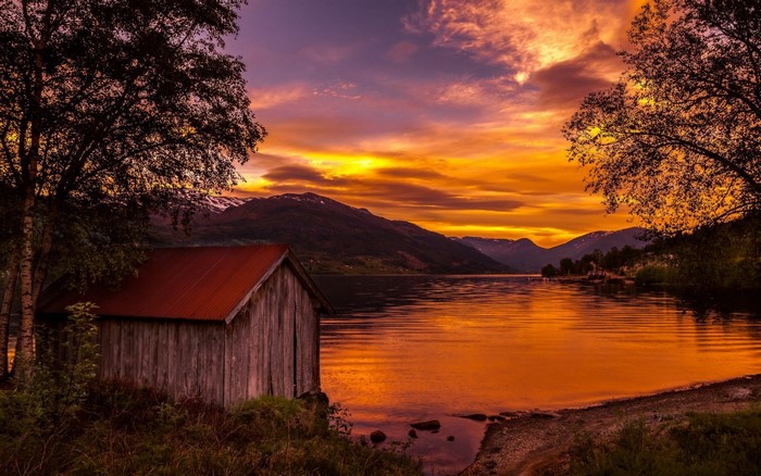 Wooden boathouse on a lake at sunset in Norway