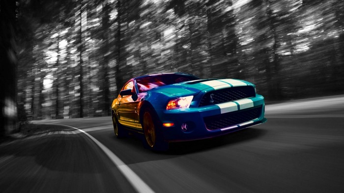 Blue Ford Mustang Shelby GT500 driving on a forest road