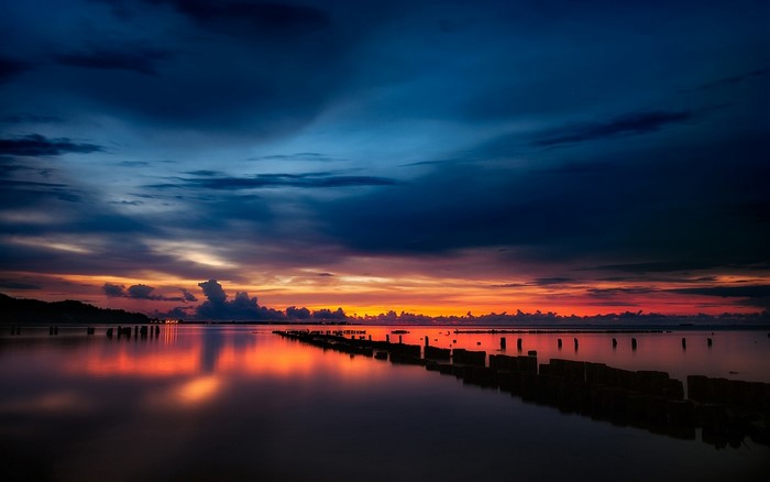 Sunset over the sea with reflections and wooden posts