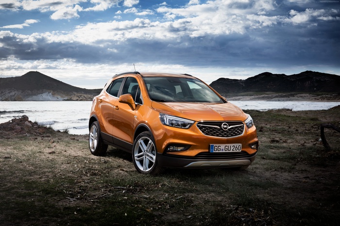 Orange Opel Mokka X SUV on a rocky shore