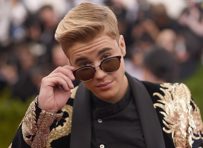 Justin Bieber wearing sunglasses and a decorated jacket