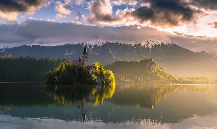Lake with island church and mountains at sunrise