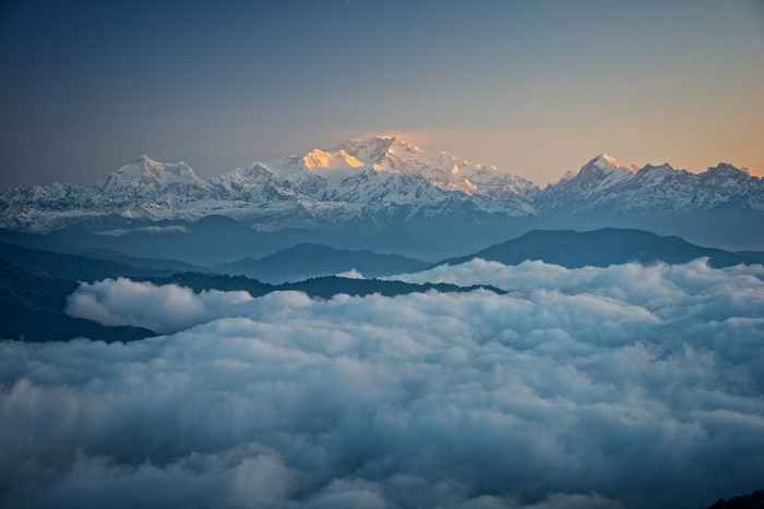 Snowy mountain range above clouds at sunrise