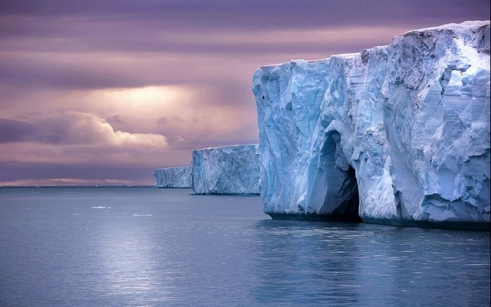Iceberg cliffs on the Arctic Ocean under a purple sky