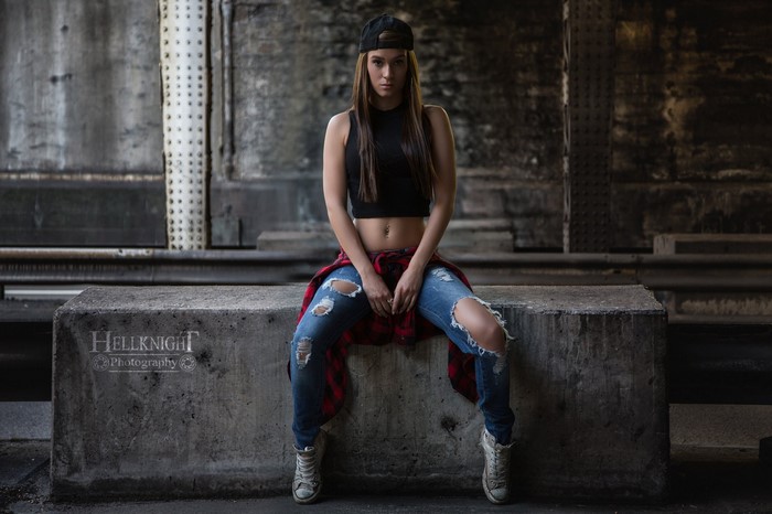 Woman in torn jeans and baseball cap sitting