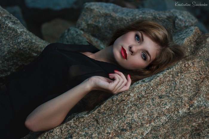 Woman with green eyes lying on rocks