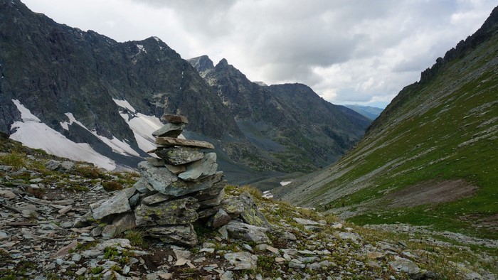Stone cairn in a mountain valley with snow patches