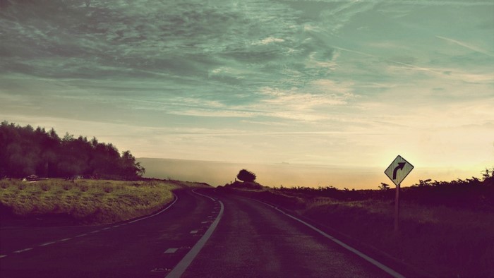 Road curving through a landscape at sunset