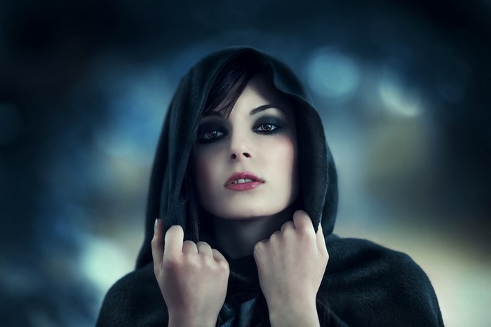 Woman in a dark hood with dramatic makeup