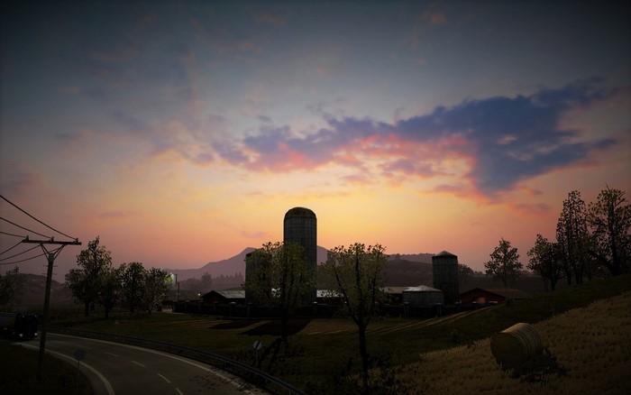 Farm silos at sunset with a road and power lines