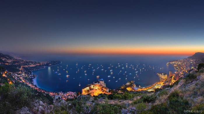 Panoramic view of Monaco coastline at sunset with numerous yachts