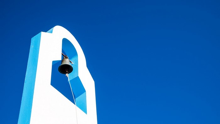 White and blue bell tower against a clear blue sky