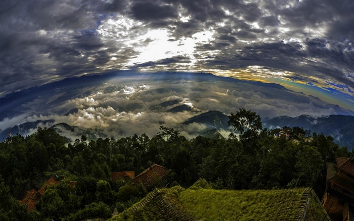 Mountain landscape with clouds and sun rays over rooftops
