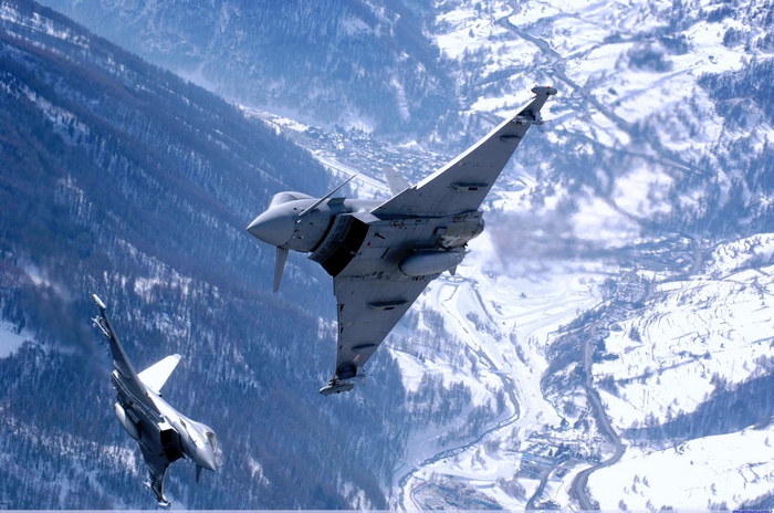 Eurofighter Typhoons flying over a snowy mountain valley