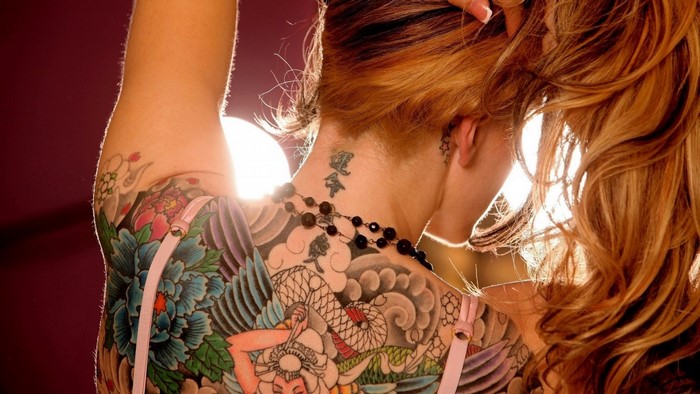 Woman with colorful back and arm tattoos