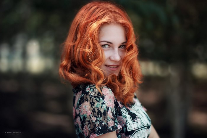 Redhead woman with curly hair in a floral top
