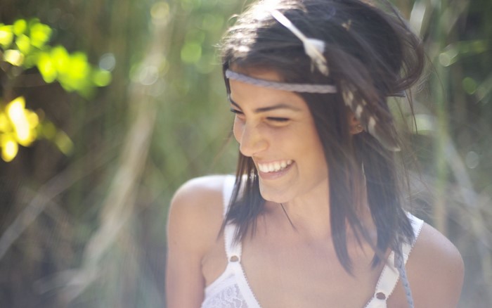 Woman with headband and feathers smiling outdoors