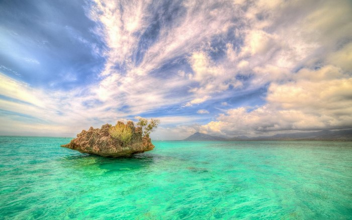Turquoise water with a rocky island and distant mountains