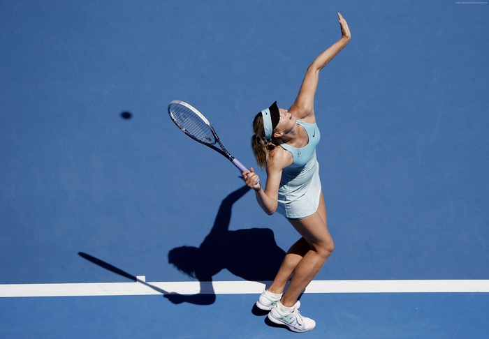 Maria Sharapova serving a tennis ball on a blue court