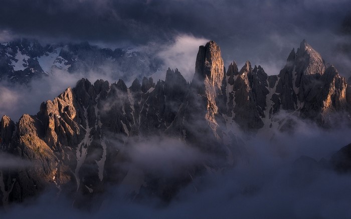 Jagged mountain peaks emerge from mist at sunrise