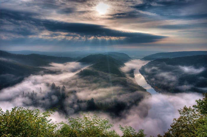 Misty river valley at sunrise with sunbeams