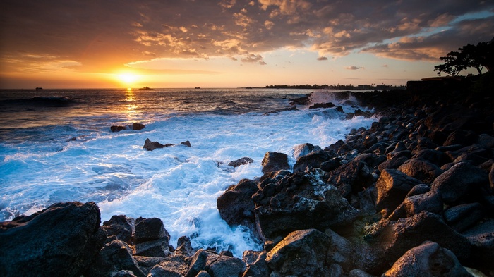 Sunset over rocky coastline with crashing waves