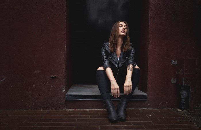 Woman in black leather jacket and ripped jeans sitting