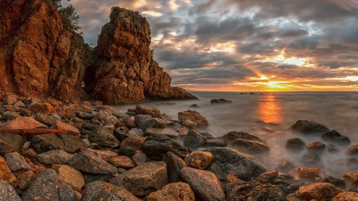 Rocky coastline at sunset with dramatic clouds