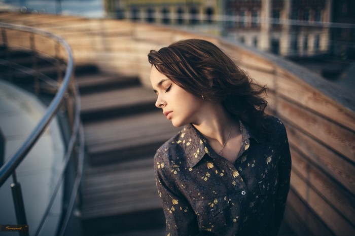 Woman with closed eyes wearing a floral shirt outdoors