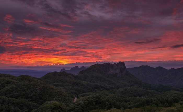 Dramatic sunset over forested mountains