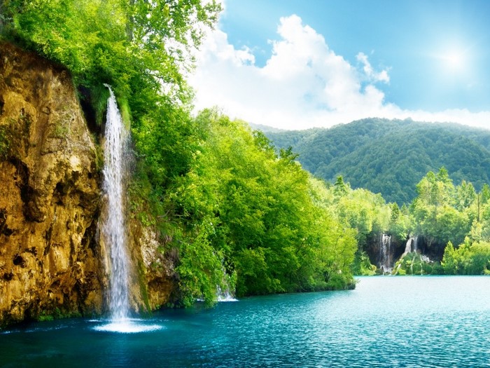 Waterfall cascading into a turquoise lake surrounded by green forest
