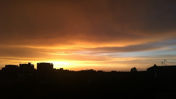 Sunset over city skyline with orange clouds