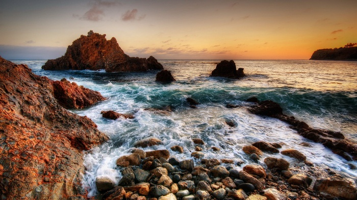 Rocky coastline with waves crashing at sunset