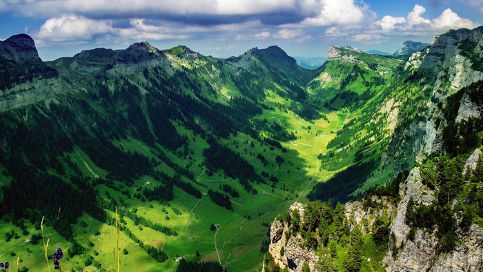 Green valley between mountains under a cloudy sky