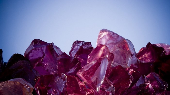 Pile of purple and red glass shards against a blue sky