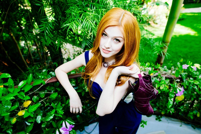 Katherine McNamara in a blue dress holding shoes