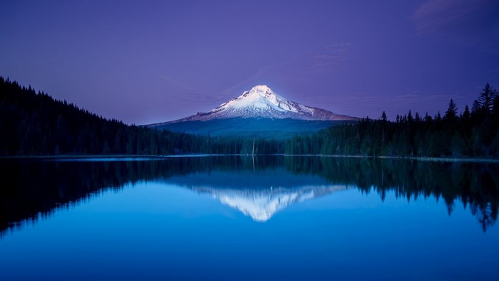 Snow-capped mountain reflected in a calm lake at dusk