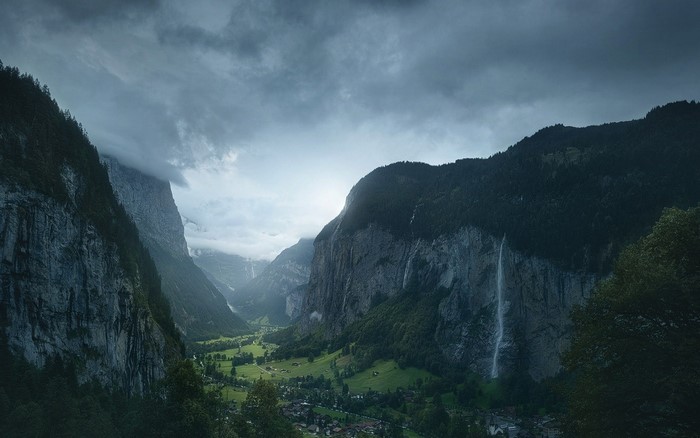 Valley with mountains, waterfall, and village in Switzerland