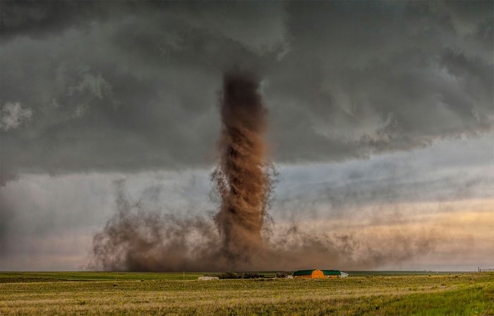 Tornado over a field with farm buildings