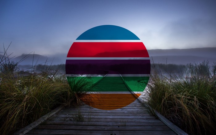 Circle with colorful stripes over a misty landscape with a boardwalk