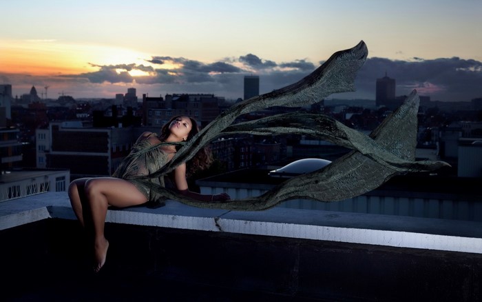 Woman on rooftop with flowing fabric at sunset